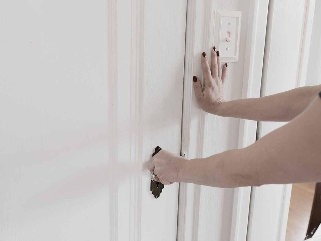 Photo of a woman trying to open a sticking door.