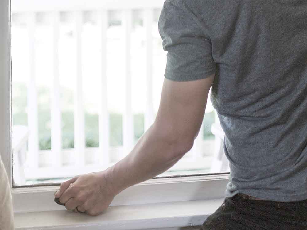 Photo of a man trying to open a sticking window.